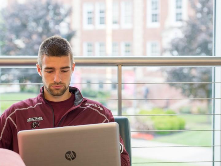 A student sitting near window with laptop